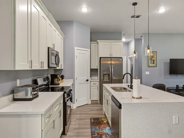 Open kitchen with abundant cabinet storage, large island with sink, and stainless appliances for everyday meal prep.