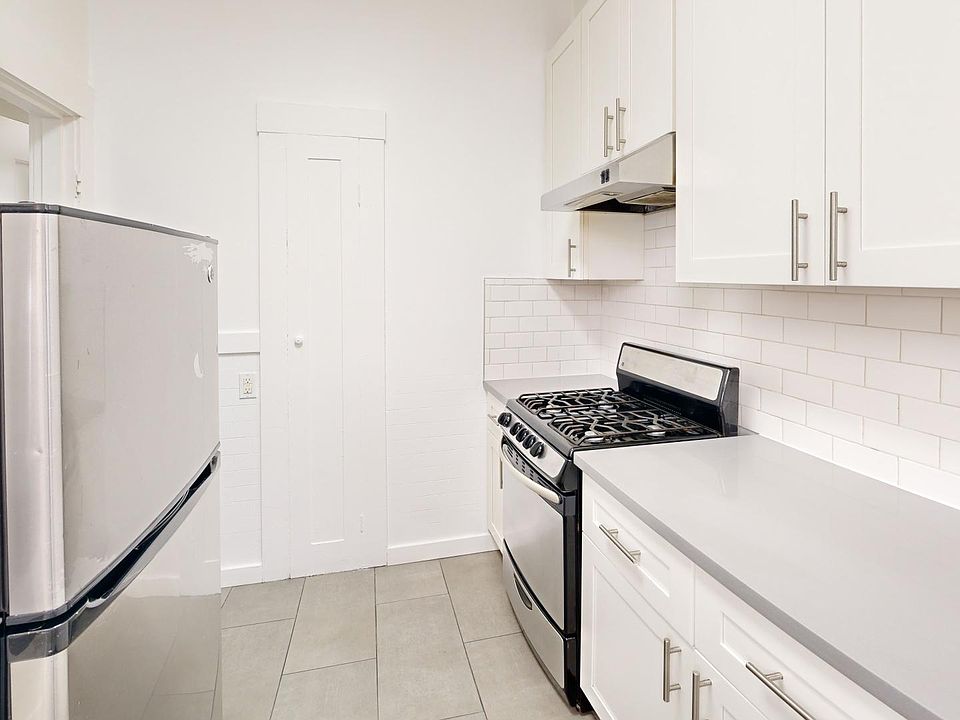 Kitchen with multiple cabinets, refrigerator, stove, and range hood