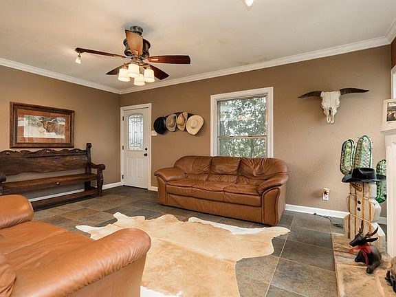 From the front door, step into the spacious living room with tile floors, crown molding, ceiling fan and fire place.