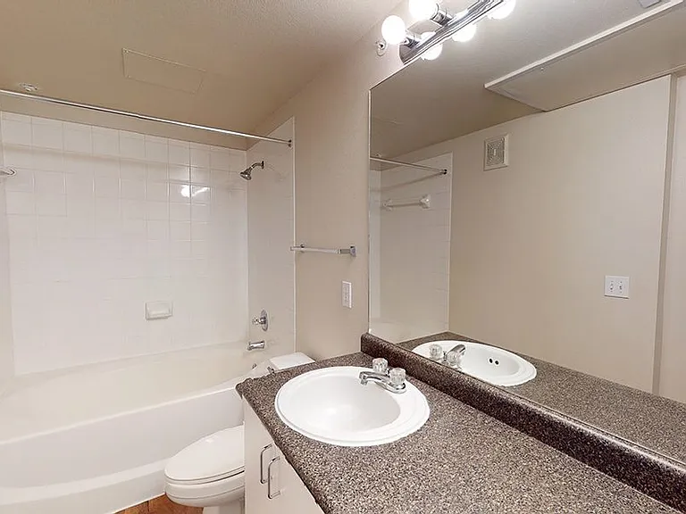 Apartment bathroom with large soaking tub and tile flooring.