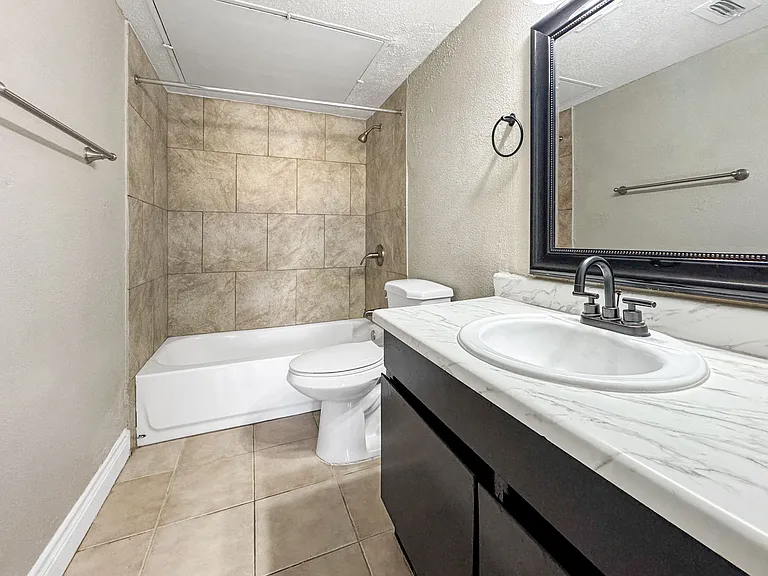 Bright bathroom featuring white tub and stylish tile surround at Borders Apartments Brownsville Texas.