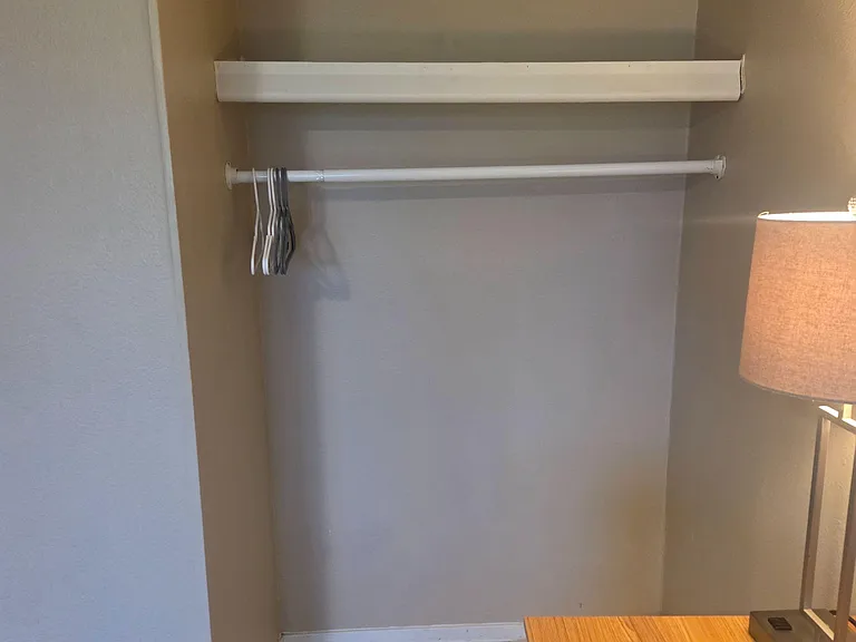 Dedicated closet storage with hanging rod and upper shelf, offering convenient space for clothing and essentials.