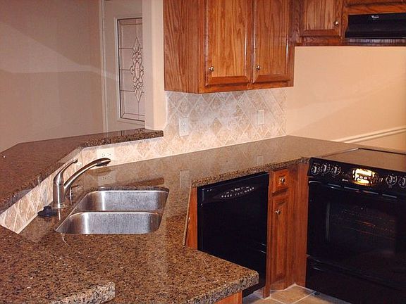 Kitchen features granite countertops and custom cabinets