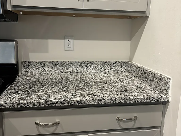 Granite countertops in kitchen in black & white flecks. Soft close cabinets, and drawers.