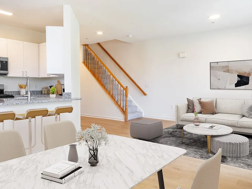 Renovated Package I kitchen, living, and dining areas with white cabinetry, grey granite countertops, stainless steel appliances, and hard surface plank flooring