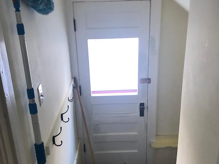 View of stairs leading to door leading to side of the house and down to basement for washer, dryer and storage.