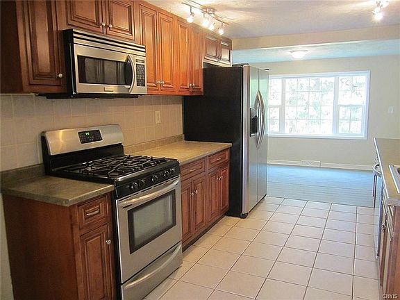 A closer look at one side of the Kitchen displays the stainless steel gas stove/oven, overhead microwave, and the side-by-side refrigerator.