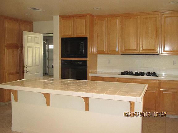 Kitchen with exit to garage. Double oven and 5-burner gas range and exhaust fan to the outside not recirculating. 3-car garage with rollup doors.