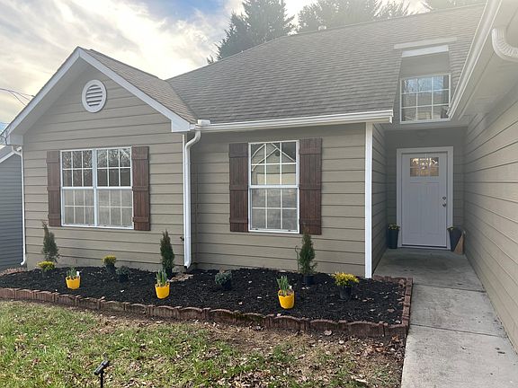 Custom wood shutters, freshly painted trim, new front door, and fresh landscaping in front garden box.