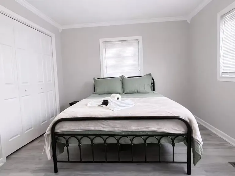 Spacious bedroom featuring a queen bed, ceiling fan, and two windows with blinds plus a wide double-door closet.