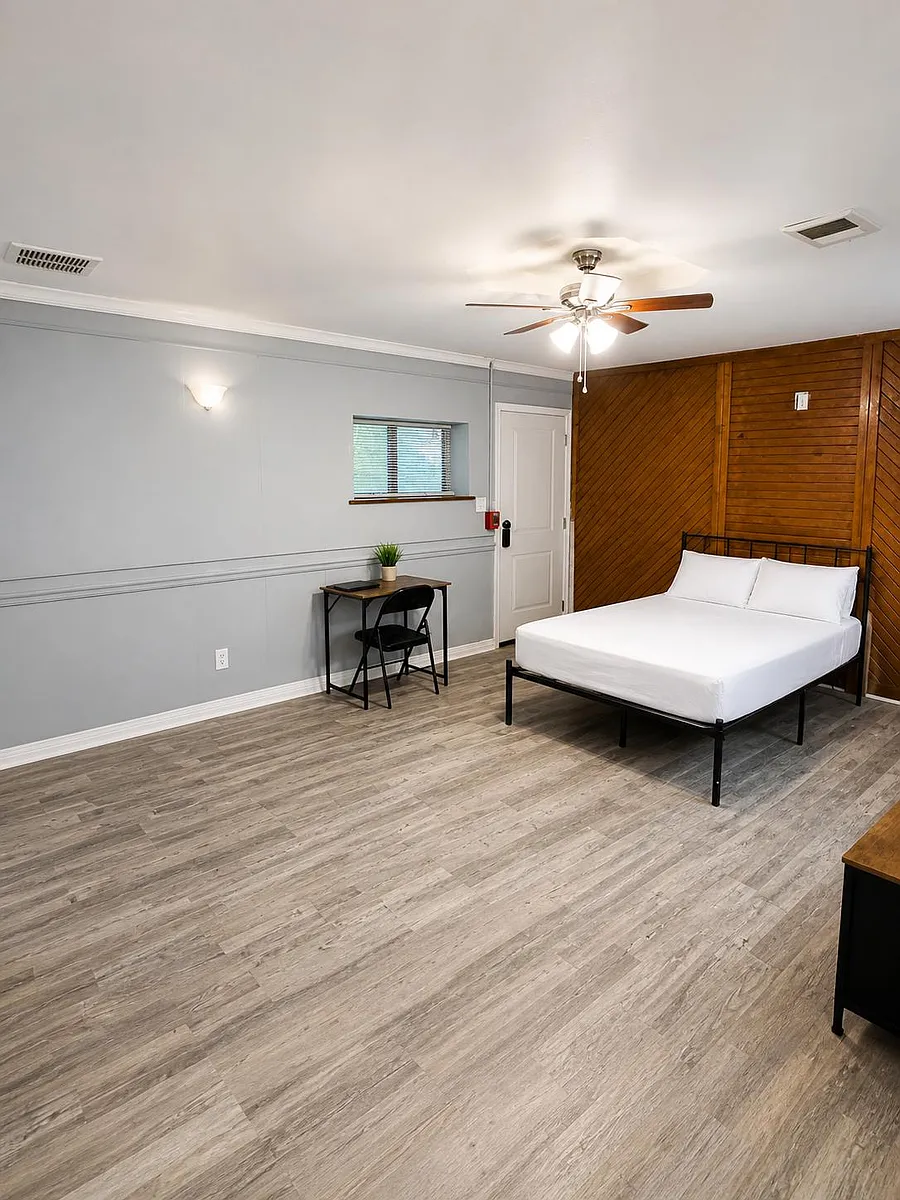 Photo 1 of 5 - Hackberry St - Lancaster, TX Spacious bedroom with a comfortable bed, dedicated desk workspace, ceiling fan, and durable wood-look flooring. - Hackberry St