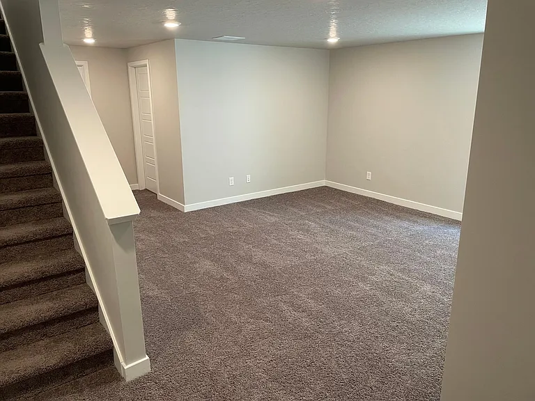 View of basement (full bathroom in far corner, utility room/storage to it's left)