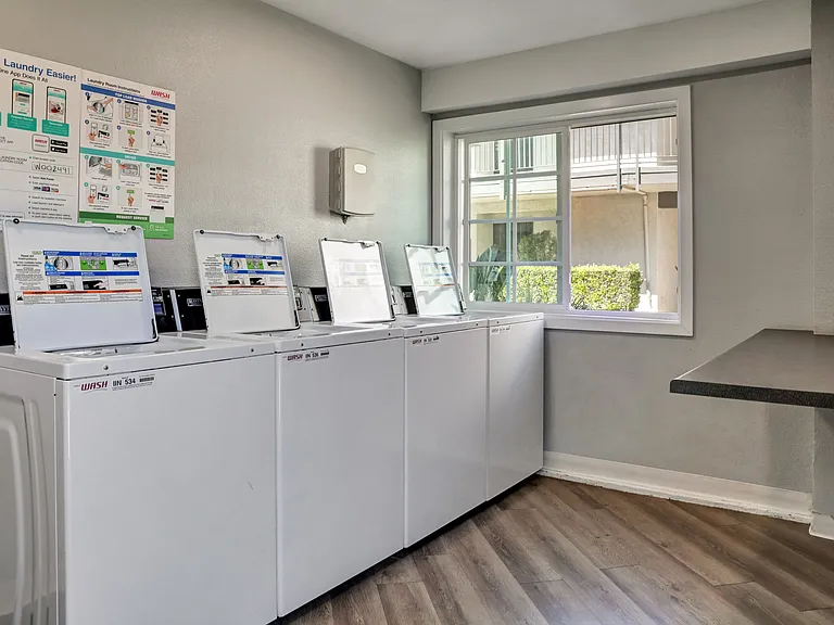 A laundry room with a row of washing machines and a signboard.