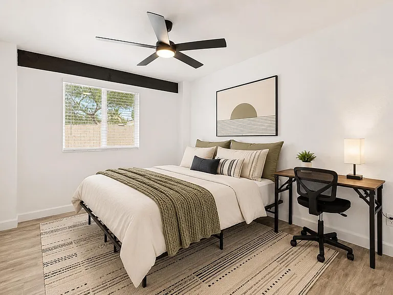 Well-appointed bedroom with a large window, ceiling fan, and dedicated desk space for work or study.