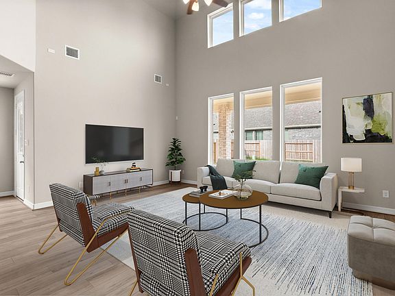 The two story family room features gorgeous flooring and huge windows that allow plenty of natural l