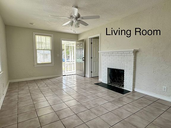 Spacious living room with tile floors, lots of natural light, and a decorative fireplace that adds charm _ plus direct access to the front porch.