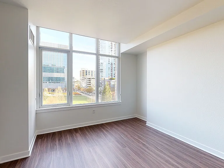 Spacious apartment bedroom with wood-style flooring.
