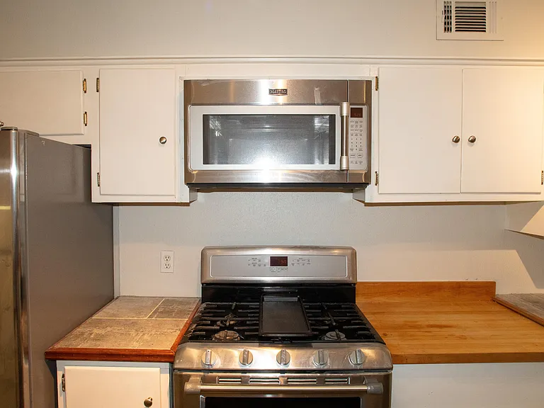 Full kitchen features plenty of cabinet space with a microwave, stove, oven, and two refrigerators.