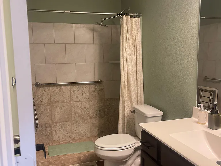 Full bathroom with a tiled tub/shower combo, vanity with sink, and convenient towel bars for everyday use.