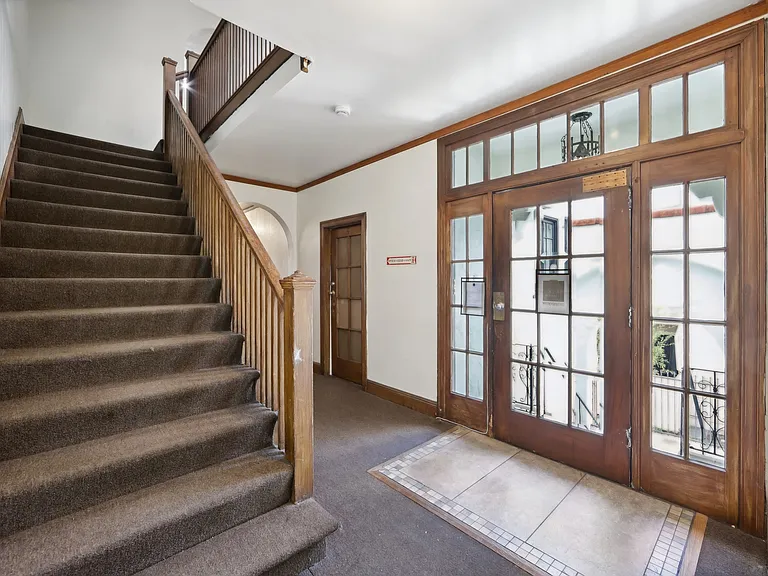Hallway with a wooden staircase and banister, a wooden door with glass window