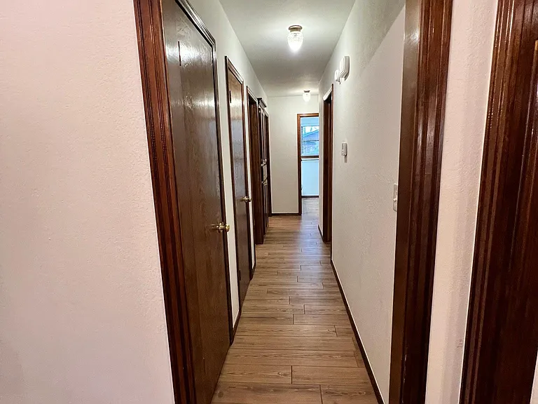 Looking from living room down hallway to bathroom. Walls are not pink but white.