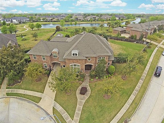 Home features automatic driveway gate and mahogany front doors, both with wrought iron details.