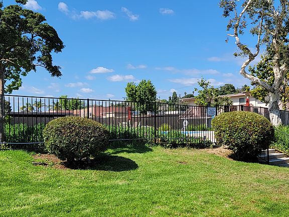 Beautiful trees and lush gardens around swimming pool at Plaza Verde Apartments in Escondido, California.