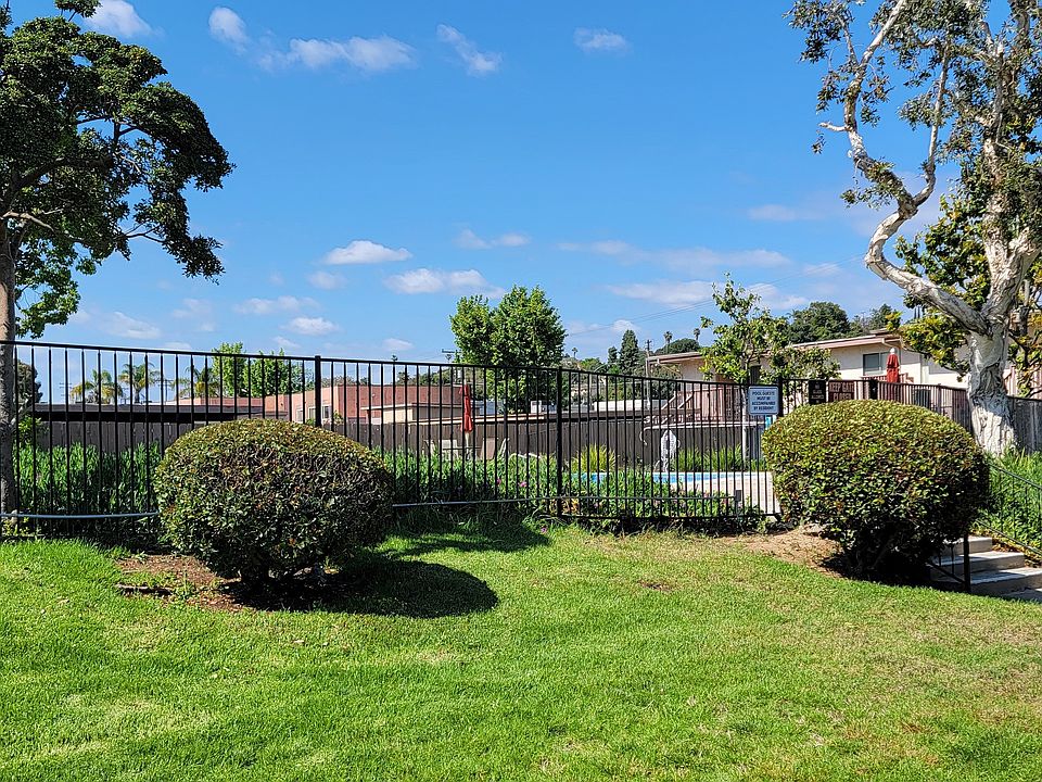 Beautiful trees and lush gardens around swimming pool at Plaza Verde Apartments in Escondido, California.