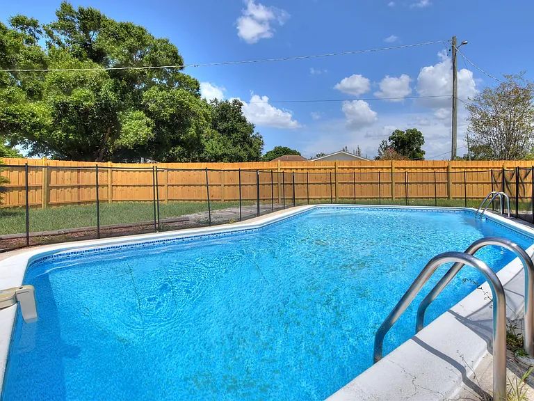 Fenced backyard pool area with a large in-ground pool, safety fencing, and open deck space for outdoor lounging.