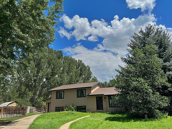 Front of the house in the summer. Large lush trees surrounds the property.