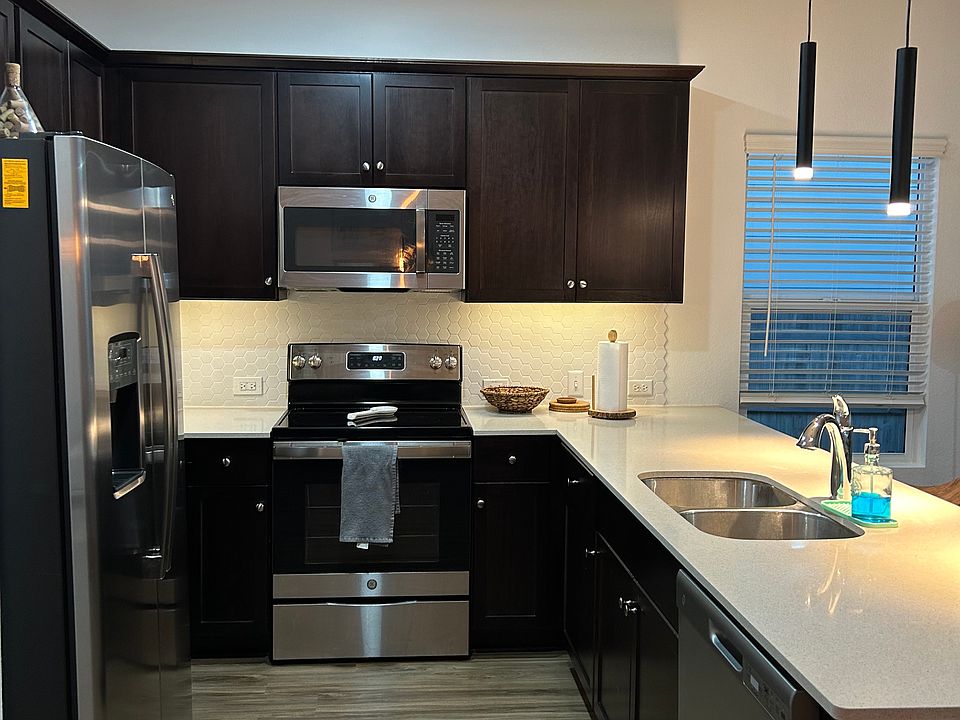 Ample kitcken, has backsplash, big counters, pendant lights.
