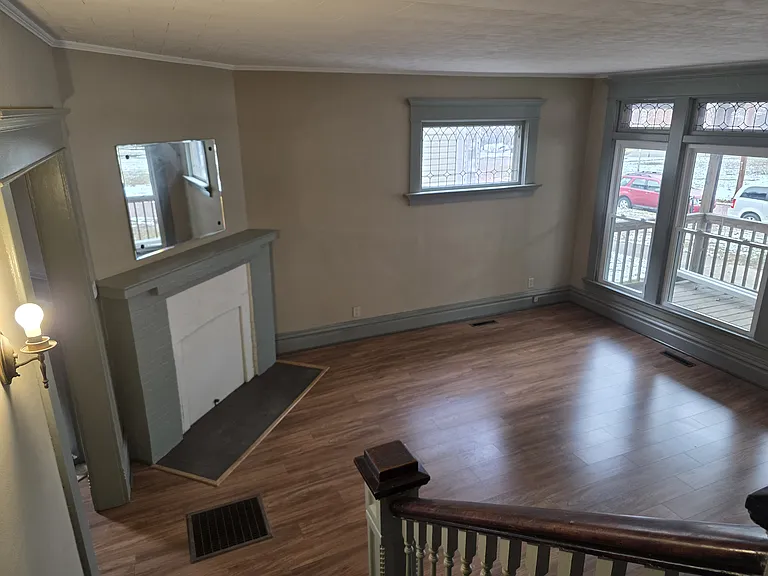 View of the living room fireplace and front windows.