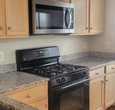 Kitchen with gas cooking stove. The refrigerator is two door, full size. The dishwasher is brand new.
