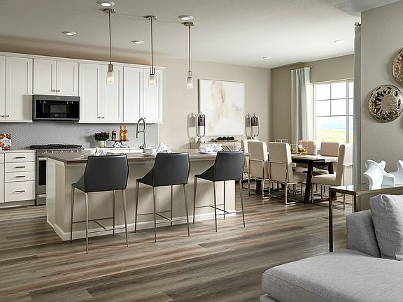 A modern and spacious kitchen with white cabinets, a large island with bar stools, and a dining area