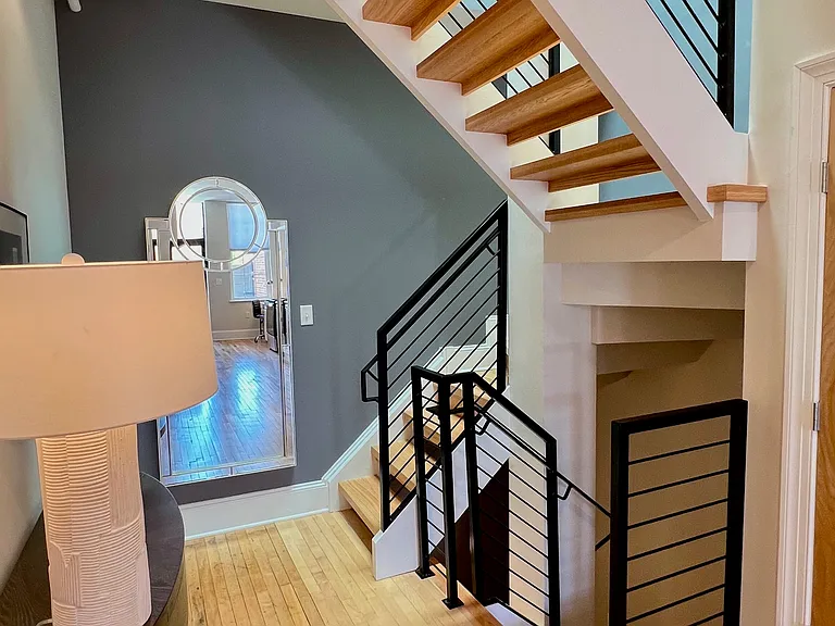 Gorgeous custom staircase leads up the the "front" door, down to the bedroom level.