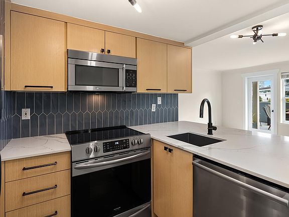 Freshly remodeled kitchen with quartz counters and stainless appliances