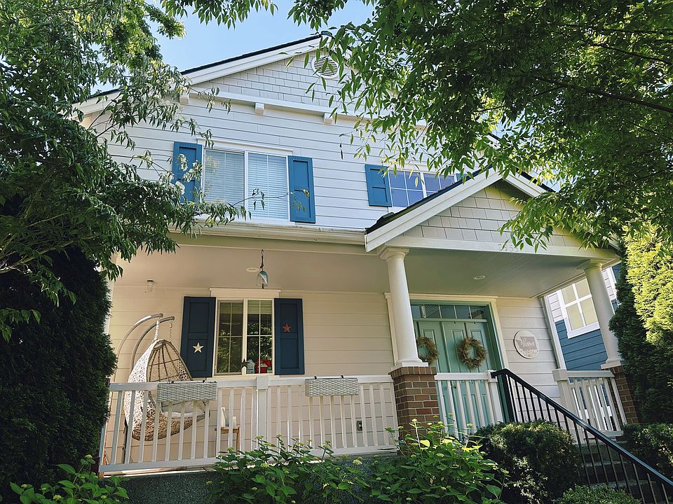 Charming Front Porch - Covered entry surrounded by lush greenery.
