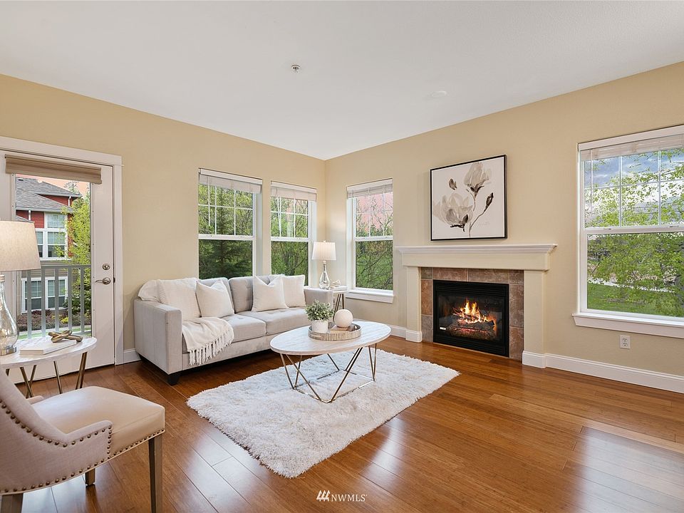 Inviting living room is warmed by cozy fireplace. Sunlit rooms and walls of windows.