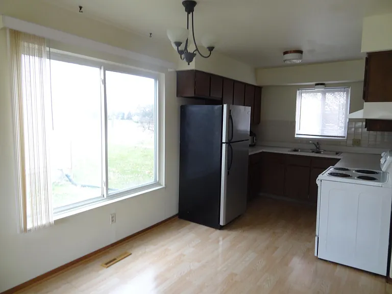 Kitchen with large window and newer fridge. Spacious dining area.