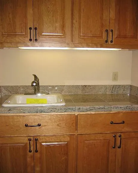 Laundry sink area, cabinets on both sides and washer and dryer with cabinets above washer and dryer as well as cabinets below