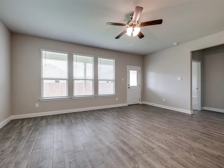 Unfurnished room featuring a healthy amount of sunlight, wood-type flooring, and ceiling fan