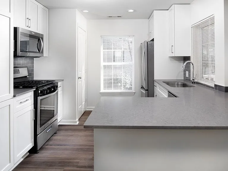 Kitchen with gray quartz countertops, tile backsplash, stainless steel appliances, and upgraded fixtures