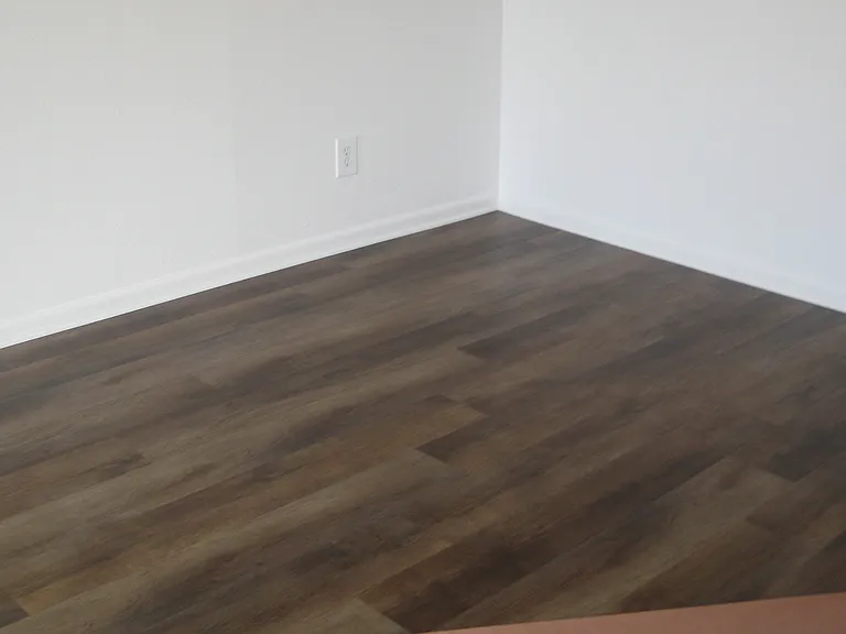 Nice vinyl plank in living room kitchen and dining area is a soft color, this picture show too dark.