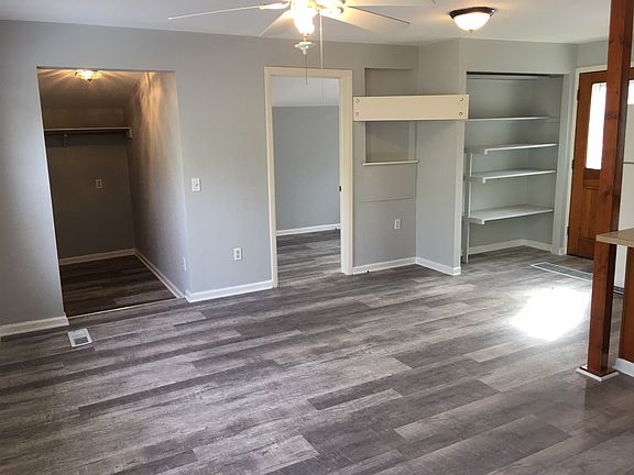 Foyer is through the left doorway, 2nd bedroom is through the doorway, White board is for mounting large screen TV, then pantry with shelves, door to the back yard is at the far right in photo.