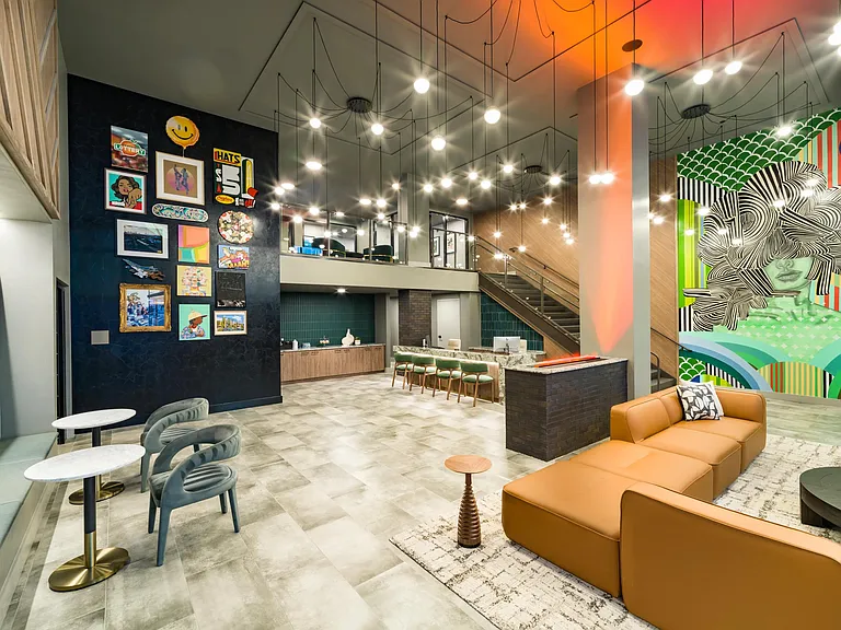 A vibrant lobby at Modera Westside Trail featuring layered lighting, curated artwork, and flexible seating that sets the tone for connection and everyday moments.