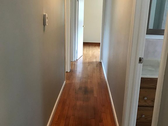 hallway from living room with full bath to the right, one bedroom straight ahead with half bath, and two bedrooms on the left