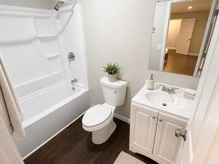 Full bath with tub/shower combo, built-in shelving, and a vanity with storage plus a large mirror.