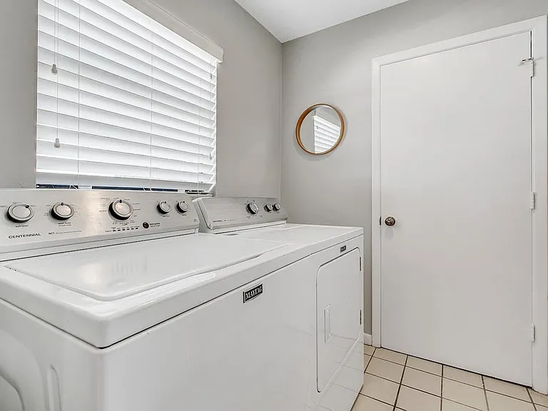 Dedicated laundry area with a full-size washer and dryer, plus a window for ventilation and easy access from the hall.