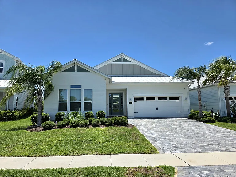 Bright, modern exterior with low-maintenance landscaping and a spacious paver drive.