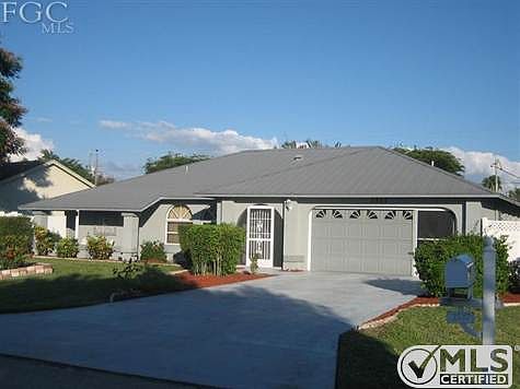 Front view, mature landscaping, metal roof.